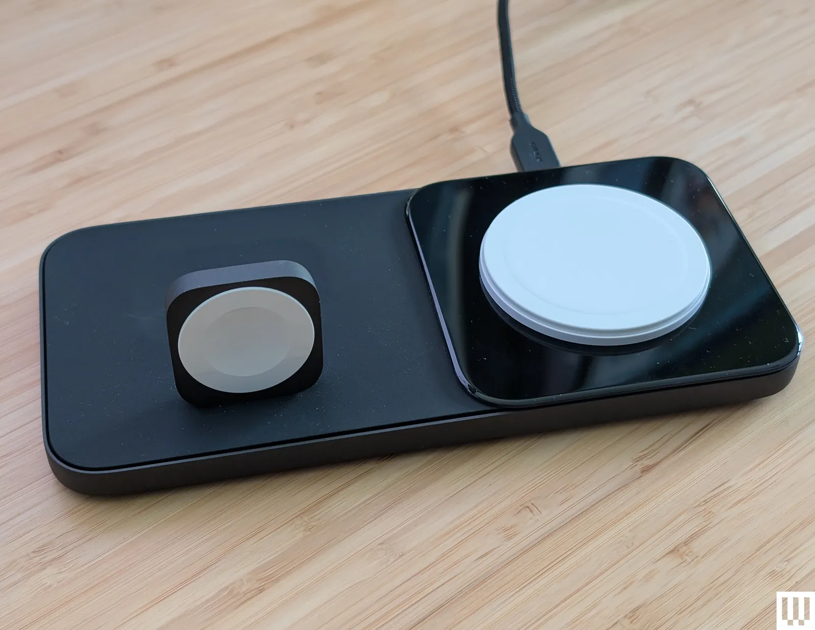 Nomad Base One Max a flat black panel with and upright square to wrap a watch around and a flat disc to place a mobile...